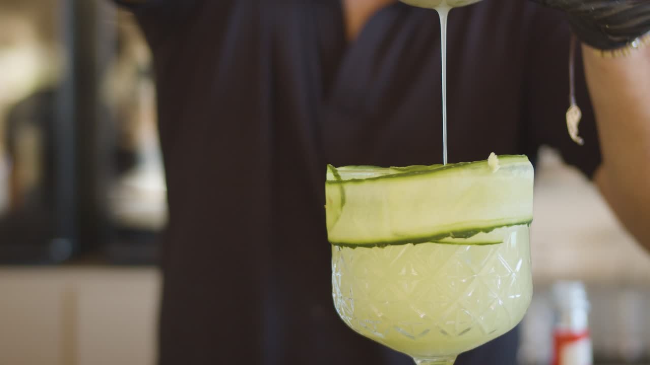 Bartender pours cocktail into glass. Slow-motion