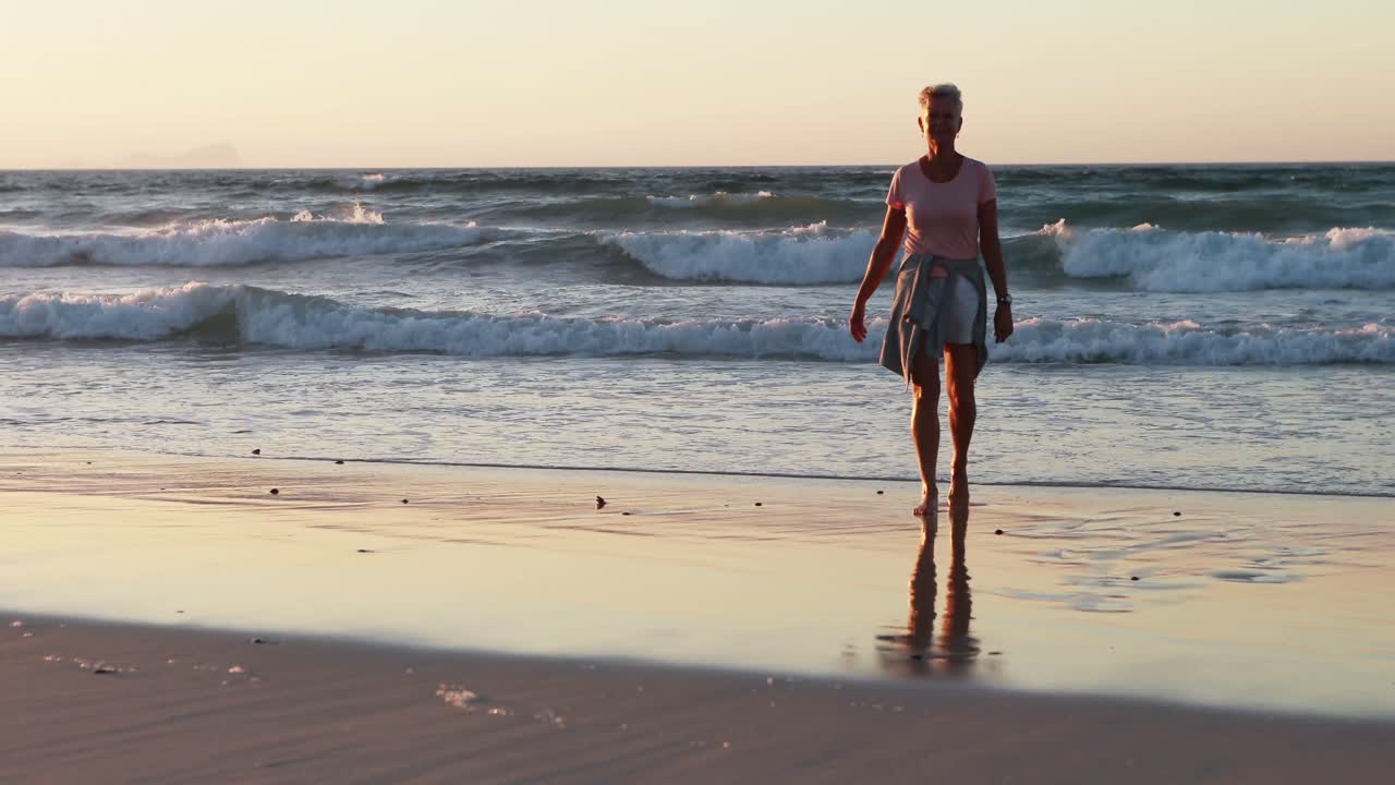 mujer mayor caminando por la playa