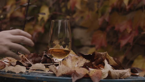 Der-Mann-Stellt-Ein-Glas-Wirbelndes-Bier-Auf-Den-Tisch-Mit-Den-Herbstblättern