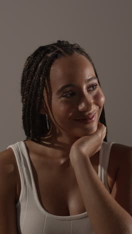 studio beauty shot of smiling young woman with long braided hair against neutral background 1