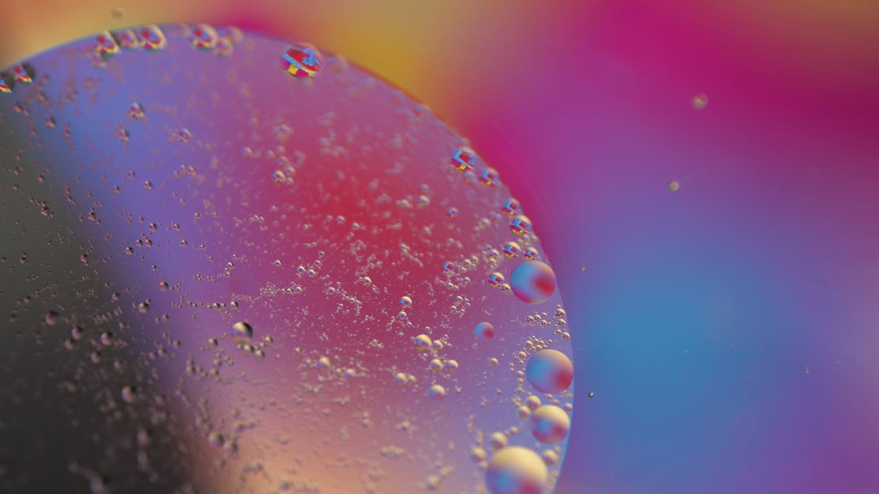 macro gota de aceite en el agua. burbujas líquidas holográficas multicolores amarillas, rojas, naranjas, púrpuras y azules