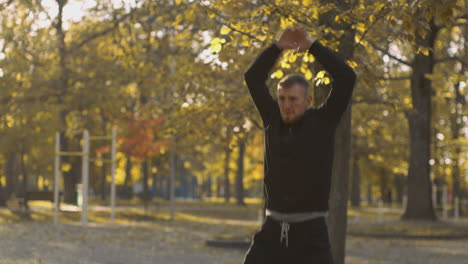 man doing jumping jacks in a park during autumn