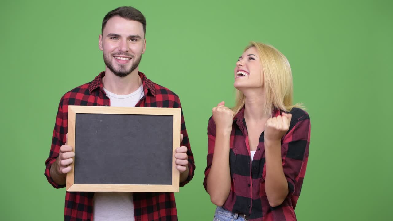 Young couple holding blackboard and looking excited together