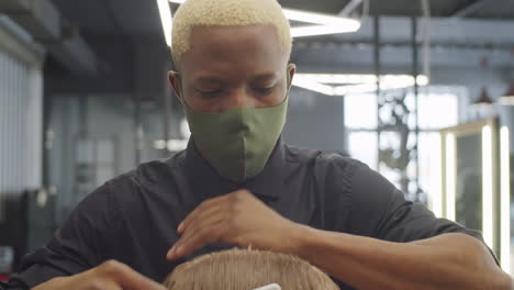 Peluquero-Negro-En-Máscara-Separando-El-Cabello-Del-Hombre