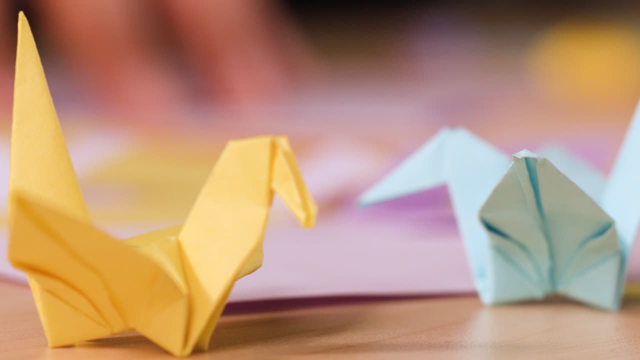 Primo piano statico di origami a forma di gru appoggiati su un tavolo da lavoro in legno
