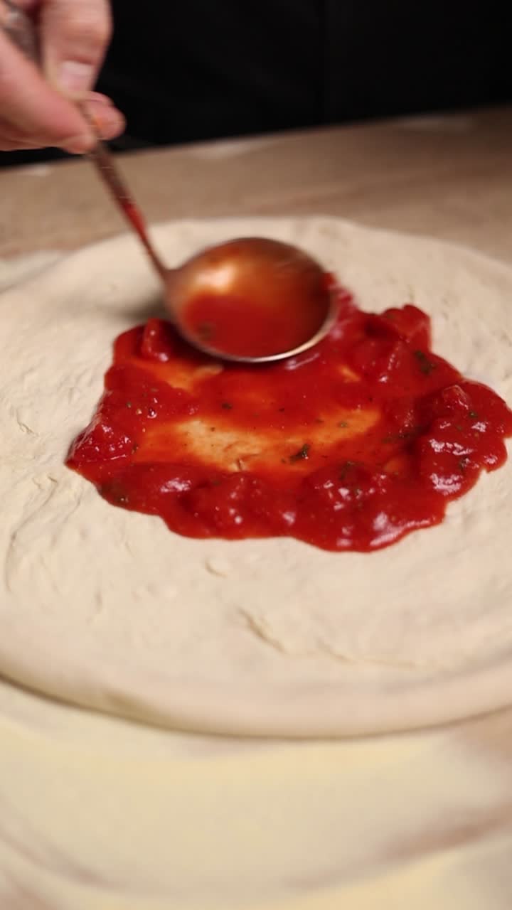 셰프가 토마토 소스와 함께 피자를 준비하고 있다