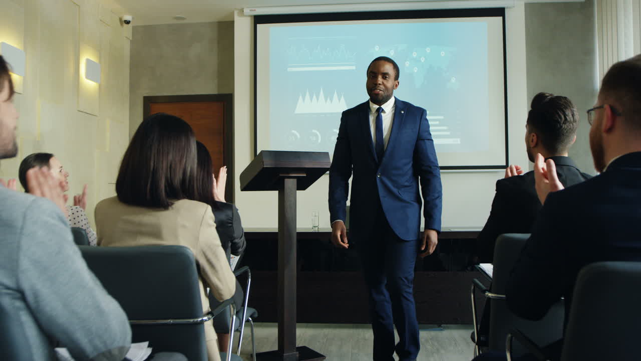 African american male business speaker finishing his conference in a meeting and going away cheerfully while people clapping