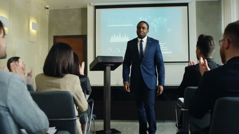 african american male business speaker finishing his conference in a meeting and going away cheerfully while people clapping