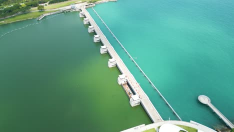 Aerial-view-over-Singapore-Marina-Barrage,-port-of-Singapore-water-dam,-panoramic-scene-showcases-the-dynamic-convergence-of-modern-engineering-and-natural-beauty