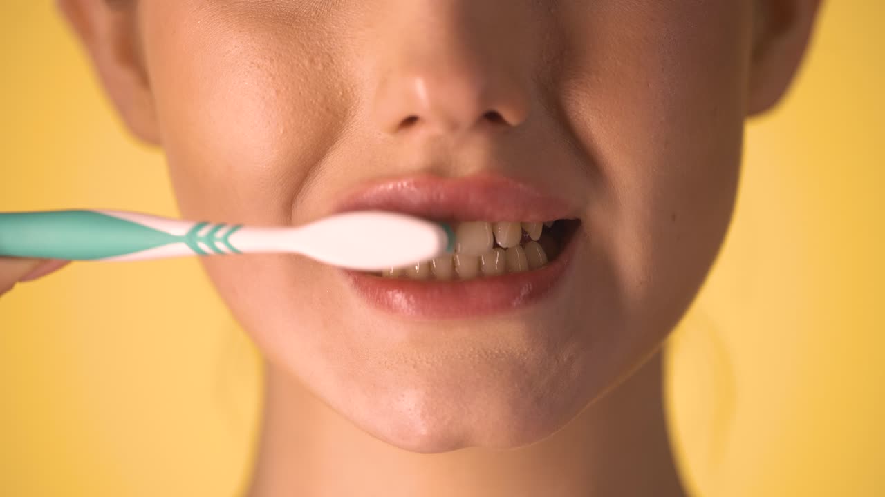 mujer caucásica se cepilla los dientes con cepillo de dientes, boca de primer plano, fondo cromático, piel blanca mujer joven modelo