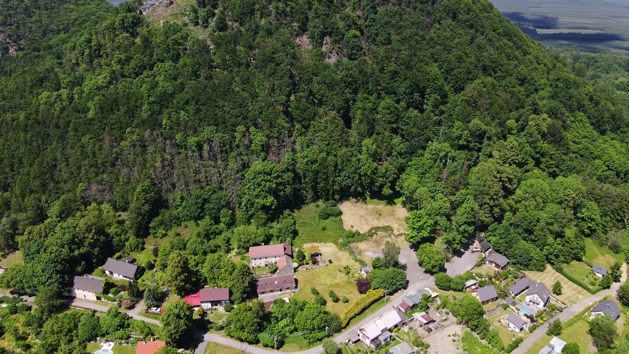 Cinematic drone tilt from Bezděz village to medieval hilltop fortress in Czechia