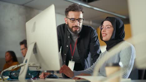 lecturer helps scholar with project, advising on their work. teacher giving lesson to diverse multiethnic group of female and male students in college room, teaching new academic skills on a computer.