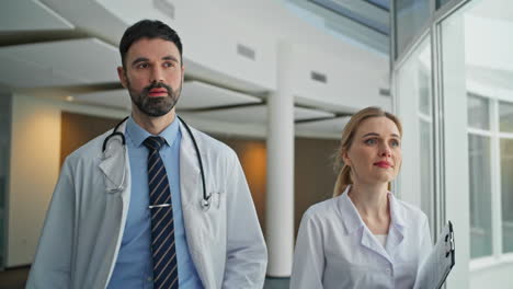 confident medics going clinic hallway closeup. smiling man pointing camera walk