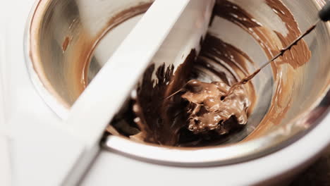 close up of melted chocolate being stirred in tempering machine