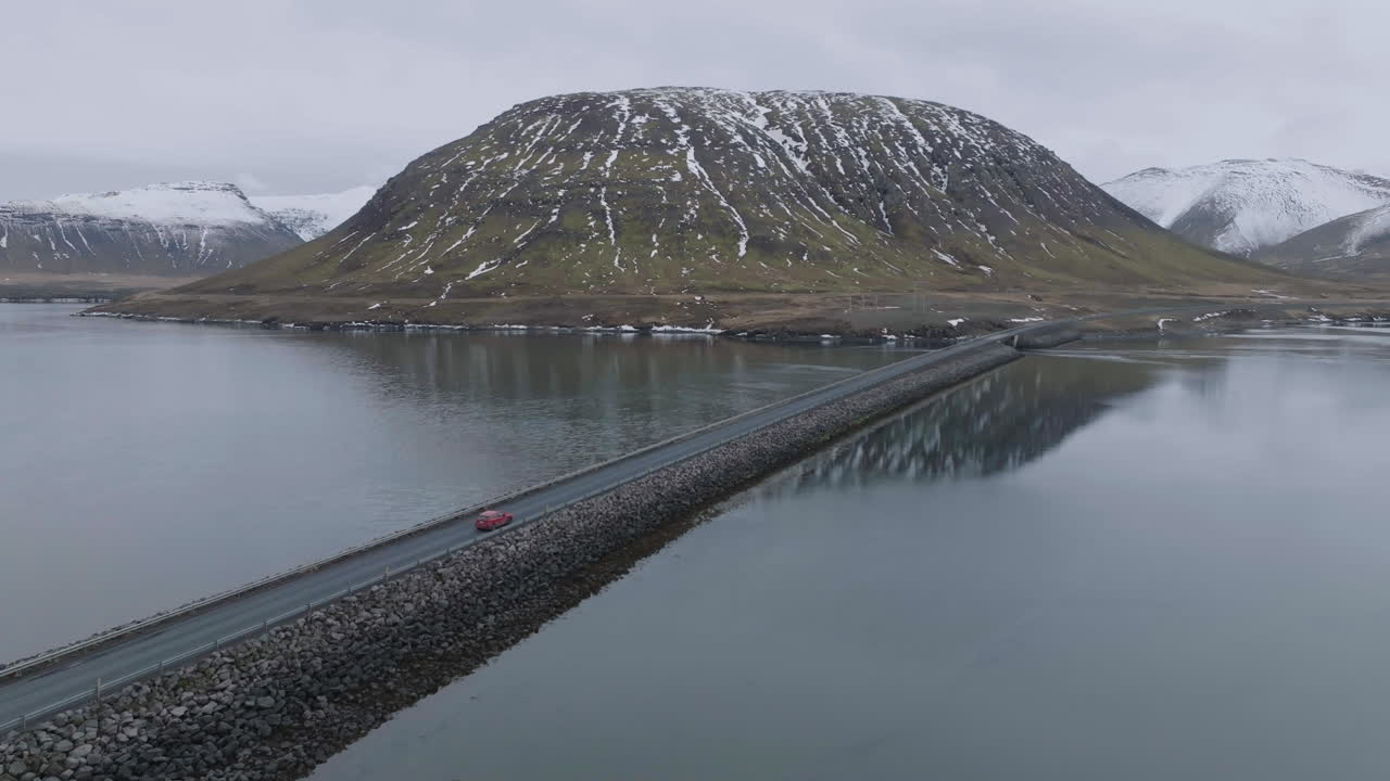 아이슬란드의 풍경에서 빙하 호수의 두 쪽 사이에 도로를 이동하는 자동차의 드론  ⁇