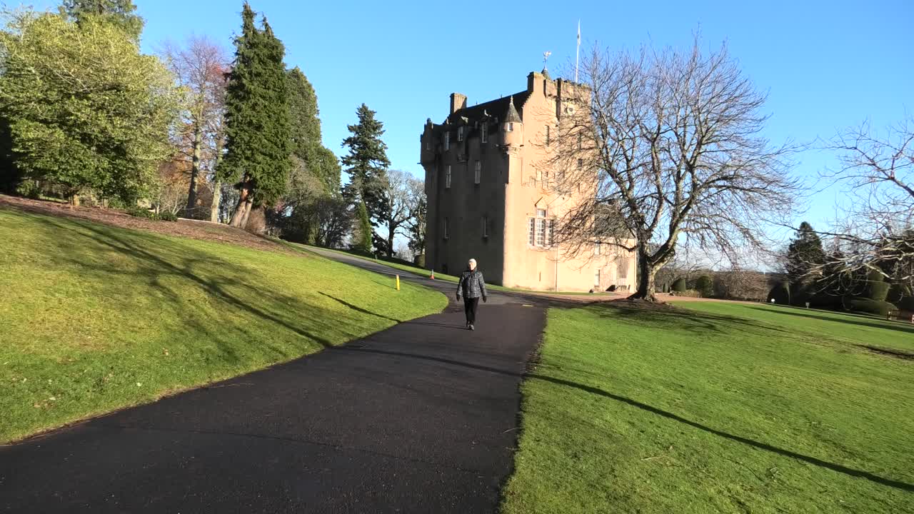 castillo de crathes en sol de invierno con una dama pasando