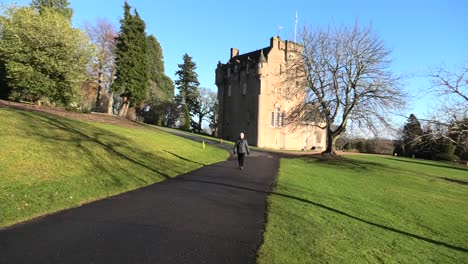 crathes castle in winter sun with lady walking past