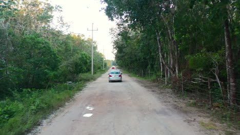 aerial-of-car-on-dirt-road-in-the-forest-of-Coba-in-Quintana-Roo-Mexico-at-sunset