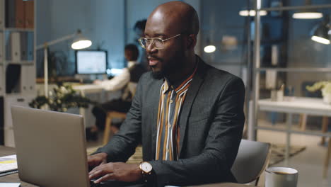 african american businessman using laptop at work in office