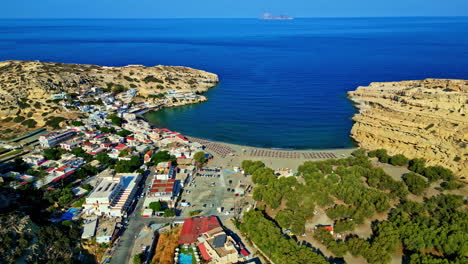aerial view of matala beach, hotels, blue sea and campground on a sunny day in matala, pitsidia, greece.