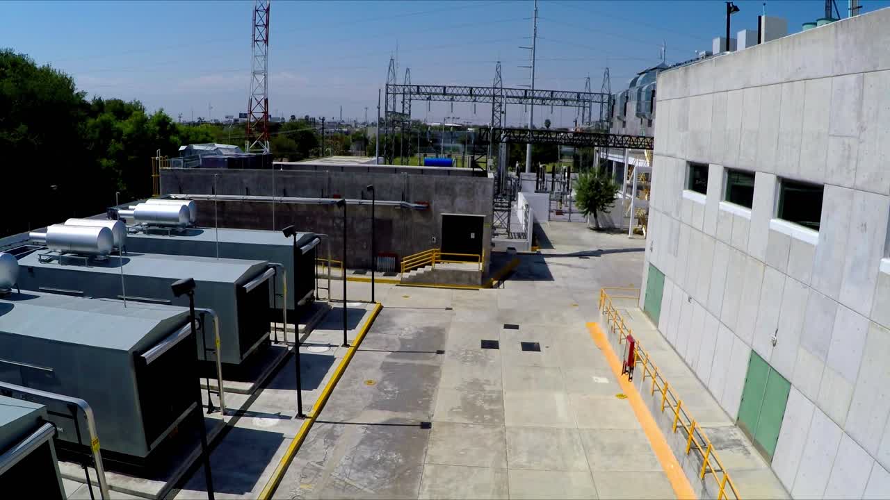 Drone view of industrial facility with machinery units pipelines and storage tanks with concrete structures and organized layout under bright daylight