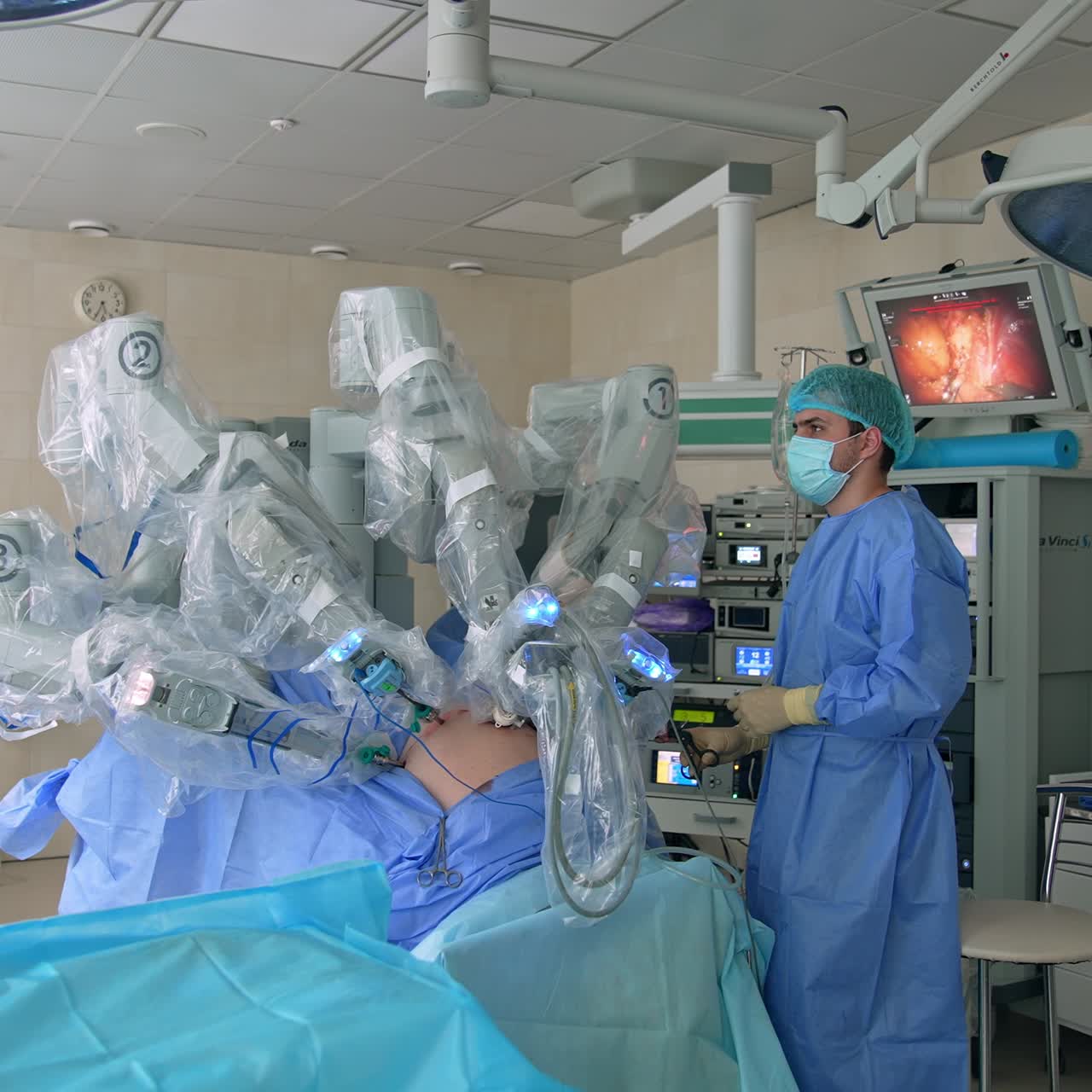 High-precise technological equipment in the middle of modern surgery room. Doctors control the work of Da Vinci robot and watch the process at screen