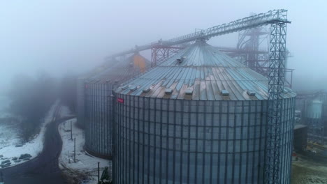 enormous silo tanks of grain elevators. metal wheat grain containers connected with each other on foggy winter day. aerial view.