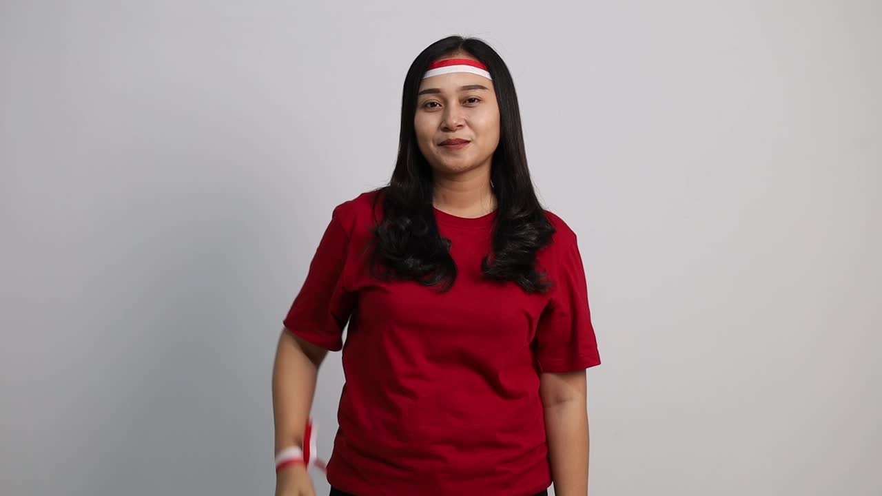 Asian woman giving salute to sideways and to the camera, celebrate Indonesian independence day on 17 August