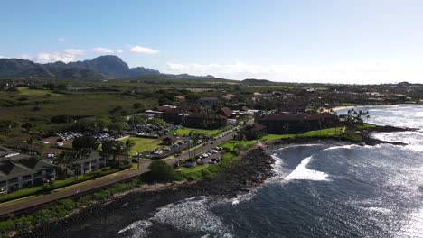 Panorámica-Aérea-Mientras-Las-Olas-Brillantes-Llegan-A-Poipu,-Hola-Con-Montañas-En-Un-Día-Despejado