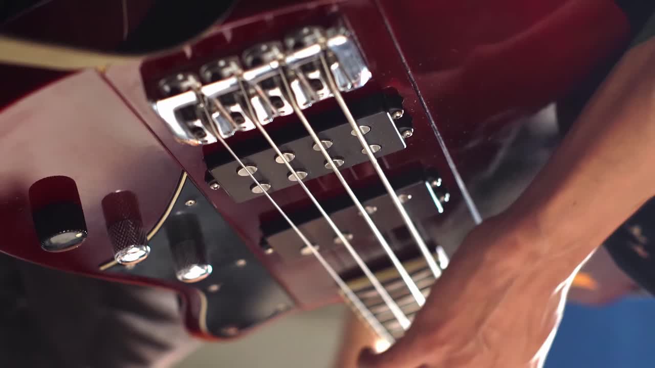 Mano di una persona che suona la chitarra elettrica, primissimo piano, vista verticale.