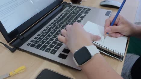 writer drafting ideas in a notebook before typing on a laptop