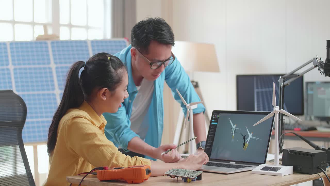 un hombre y una mujer asiáticos discuten el trabajo con un panel de células solares y una computadora portátil que muestra una turbina eólica