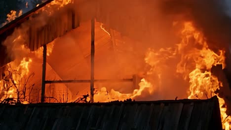 wooden barn rapidly engulfed by intense flames, smoke billowing into evening sky, structure burning down in dramatic rural setting