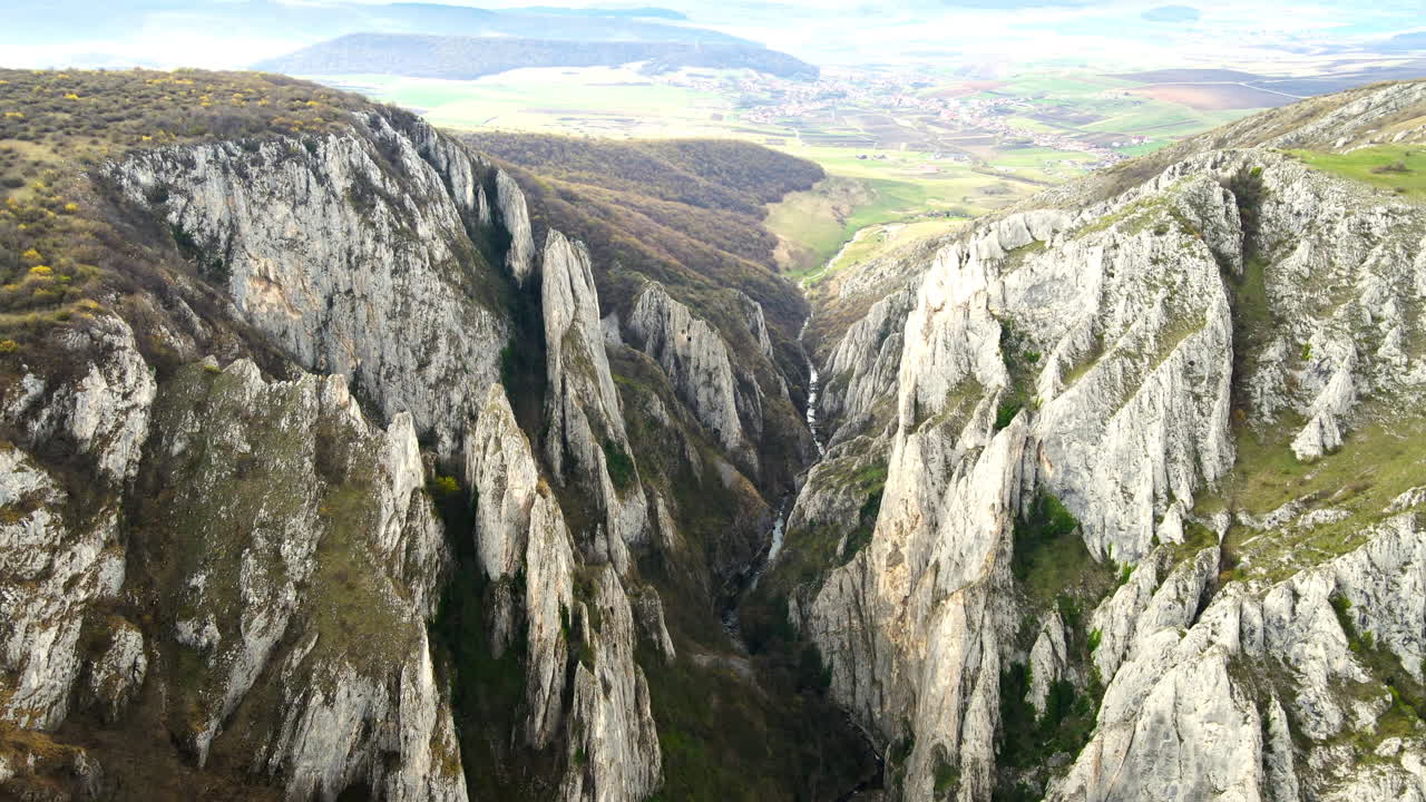 Vista aerea da drone di un canyon roccioso in Romania. Scogliere rocciose con vegetazione rada. Campi e colline circostanti