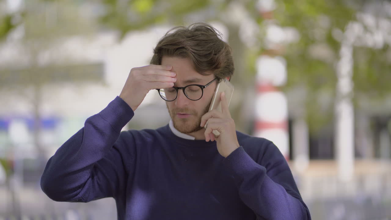 hombre dudoso hablando por teléfono inteligente al aire libre