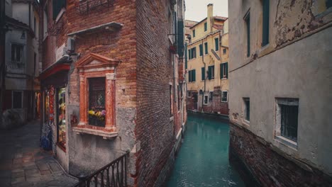 seamless video loop / cinemagraph of a venetian canal with a bridge among the old medieval houses in the old town city center of famous unesco heritage site venice in italy with clear blue water and ships and boats in the tourist vacation location.