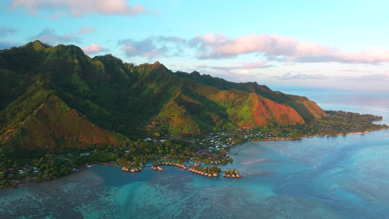 Golden hour sunny sunset water bungalows Cooks Opunohu Bay Moorea island French Polynesia aerial drone Mount Mauaroa Tohivea Rotui clouds boats lagoon coral reef waves Pacific Ocean circle right