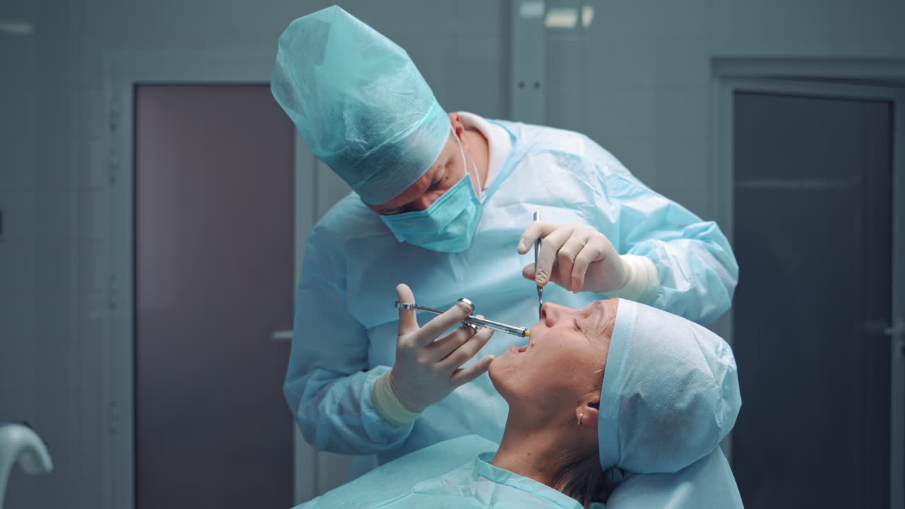 Dentist in medical clothes is doing anesthetic injection in the sick tooth. Stomatologist man treating female patient in the dentist office. Stomatology anesthesia