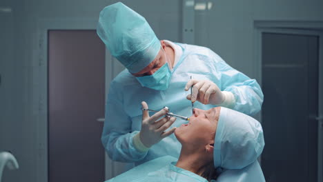 dentist in medical clothes is doing anesthetic injection in the sick tooth. stomatologist man treating female patient in the dentist office. stomatology anesthesia