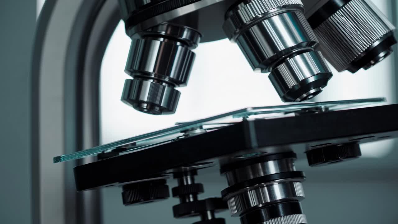Close-up video shot of a microscope from a low angle, highlighting the intricate details