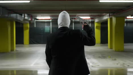 man in a suite with a white mask pointing a gun to his head