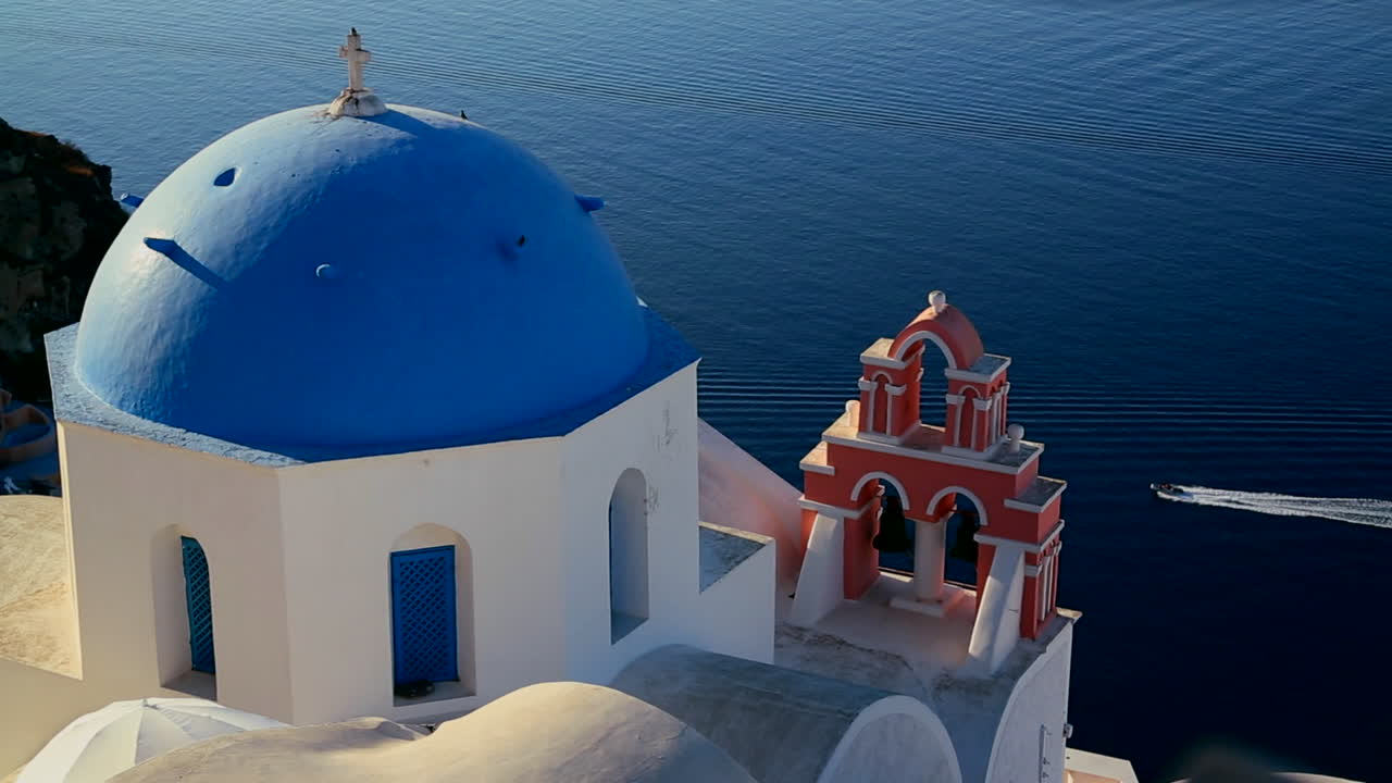 un barco pasa por una iglesia ortodoxa griega en la isla griega de santorini