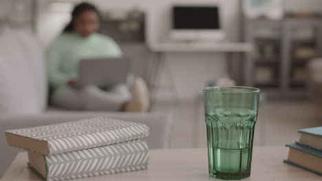 glass and books lying on desk in living room
