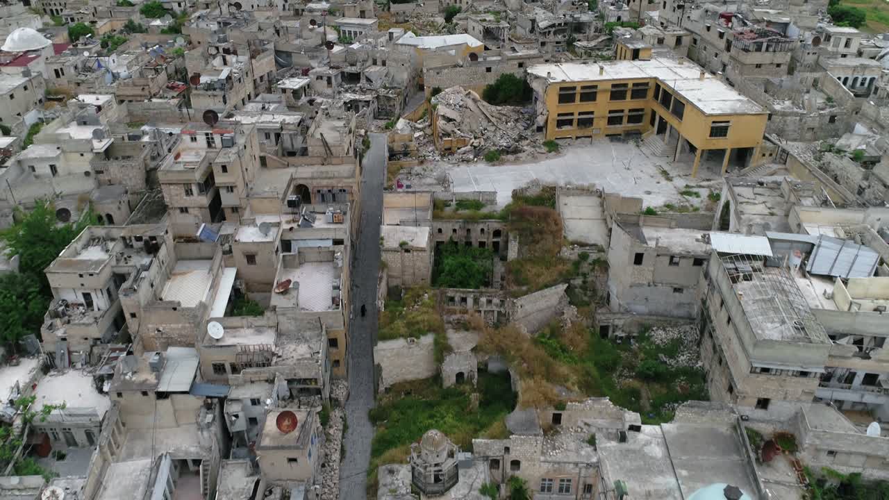 Drone che sorvola le case ad Aleppo sotto un cielo nuvoloso. Si possono vedere gli edifici e le case della città siriana in rovina dopo la guerra 4K