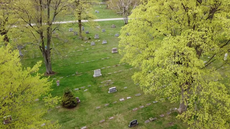 Riprese aeree con drone di un cimitero a Grand Rapids, Michigan, con fogliame verde, alberi e lapidi.