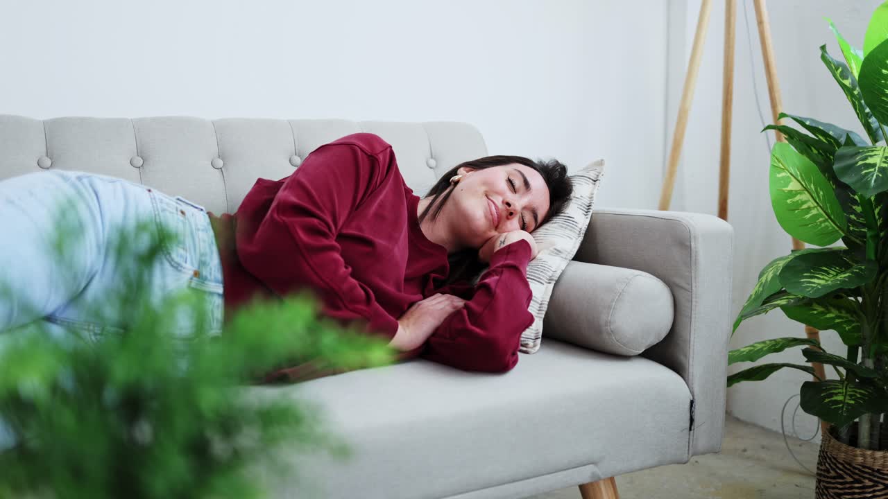 Wanita Muda yang Tenang Berbaring di Sofa dan Tersenyum