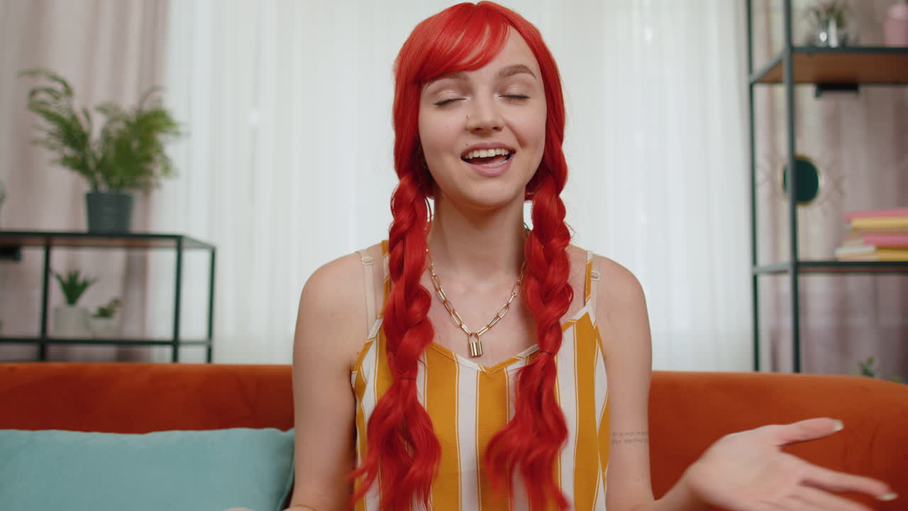 가정 소파에 앉아 카메라를 보고 친구나 부모와 비디오 컨퍼런스 통화를 하고 있는 여성