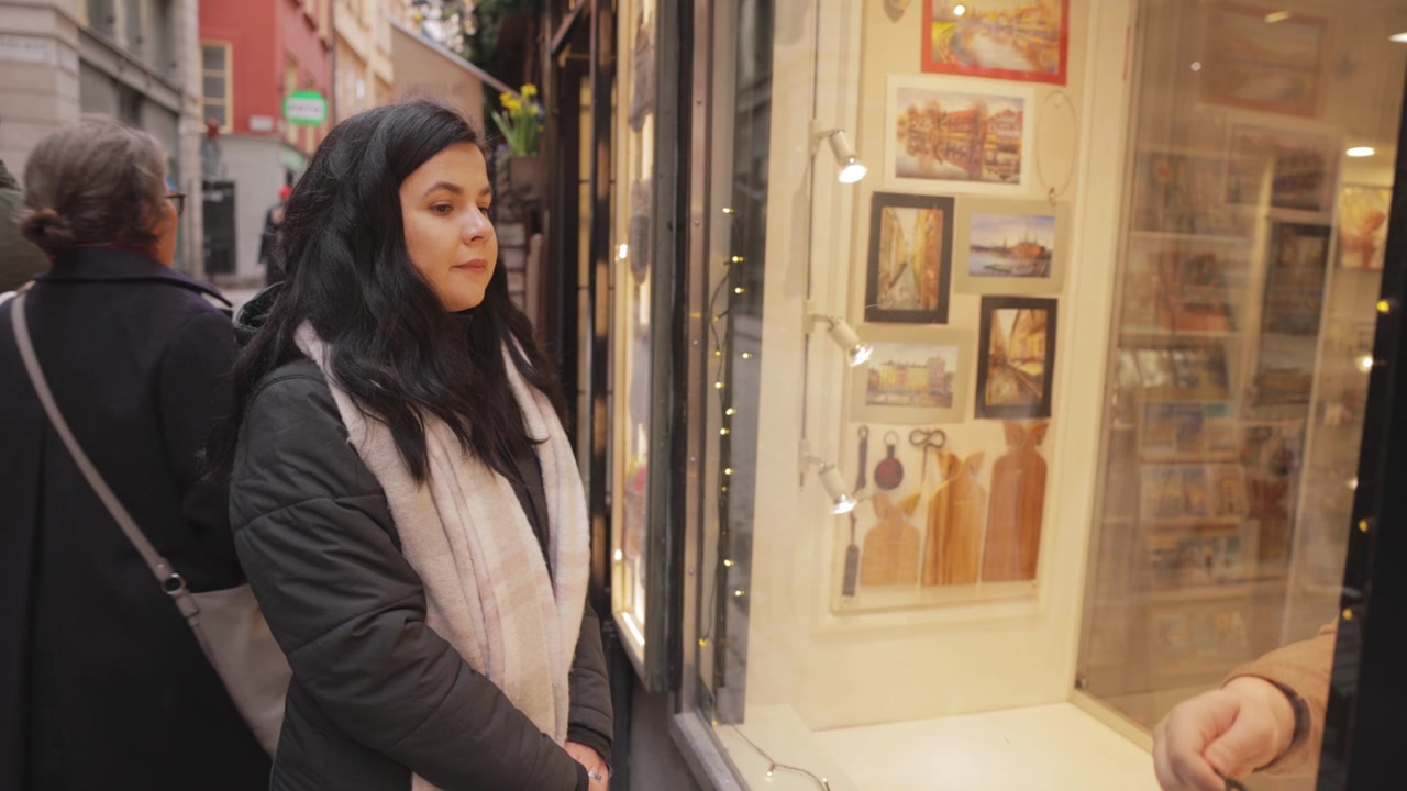 Turista morena olhando para a vitrine de uma loja em Estocolmo, Suécia. Plano médio