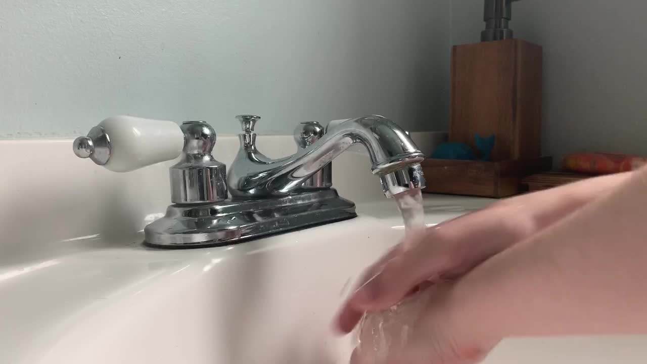 Child washes their hands in a white sink