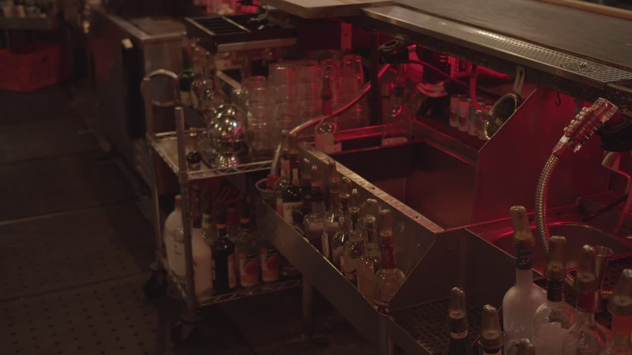 botellas en la parte trasera del bar, diferentes tipos de vidrio en el inventario, atmósfera rústica y vintage, capturada durante el rodaje de un video musical para una banda de rock